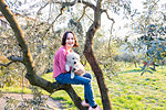 Girl holding a cute golden retriever puppy on tree in orchard, portrait, Scandicci, Tuscany, Italy