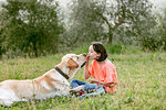 Girl sitting face to face with labrador dog in field landscape, Citta della Pieve, Umbria, Italy