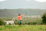 Girl running with labrador dog in scenic field landscape, Citta della Pieve, Umbria, Italy