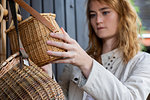 Young woman looking at wickerwork basket in shop