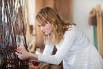 Young female basket maker weaving in workshop