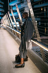 Stylish man leaning against bridge railings using cellphone, Milan, Italy