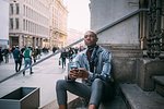 Stylish man sitting on steps of building, Milan, Italy