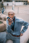 Stylish man using cellphone in piazza, Milan, Italy