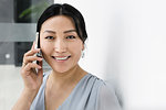 Businesswoman using smartphone against white wall in office