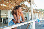 Happy, carefree young woman relaxing on beach hut patio