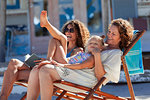 Playful, happy multi-generation women relaxing on sunny beach