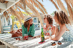 Women friends drinking cocktail and beer and sunny beach bar