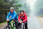 Portrait father and son mountain biking in rain