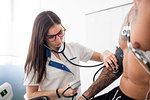 Nurse performing ECG test on patient in consultation room