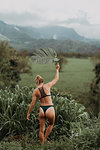 Woman in bikini holding large leaf, Princeville, Hawaii, US