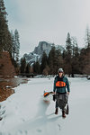 Man dragging kayak across snow, Yosemite Village, California, United States
