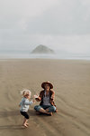 Mother and toddler playing with sand on beach, Morro Bay, California, United States