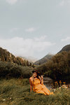 Woman in orange maxi dress sitting by rural valley river, Mineral King, California, USA