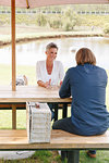 Couple with picnic basket relaxing by pond, Cape Town, South Africa