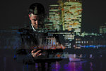 Double exposure businessman using smart phone against cityscape at night