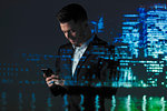 Double exposure businessman using smart phone against highrise lights at night
