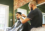 Male barber giving customer a haircut in barbershop