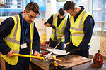 Male students using equipment in shop class workshop