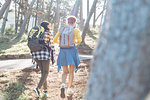 Young women friends with backpacks hiking in sunny woods