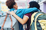 Affectionate young women friends with backpacks hugging