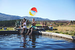 Portrait playful brother and sister with beach ball at sunny, summer poolside