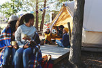 Lesbian couple watching kids playing with soccer ball outside camping yurt