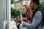 Couple using smartphone at window display