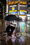 Man riding a bicycle on rainy night