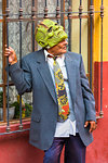 Man wearing suit jacket and necktie with a green monster mask on his head standing in street in San Miguel de Allende, Guanajuato, Mexico