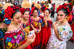 Group of women dancers wearing traditional dresses taking a selfie at a St Michael Archangel Festival parade in San Miguel de Allende, Mexico