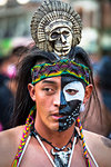 Indigenous tribal dancer with half painted face and wearing headdress with skull at a St Michael Archangel Festival parade in San Miguel de Allende, Mexico