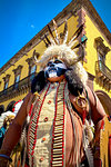 Portrait of an indigenous tribal dancer wearing black and white face paint and headdress with cattle horns at a St Michael Archangel Festival parade in San Miguel de Allende, Mexico