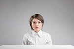 serious inexpressive woman portrait in front of an work table on a gray background with lots of copyspace