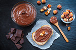 Slice of bread with spread chocolate cream and hazelnuts on black table. Serving a delicious breakfast concept.