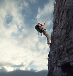 Explorer man climbs a high danger mountain with a rope