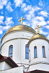 Fragment of the Orthodox Church with white walls and golden domes against the blue sky
