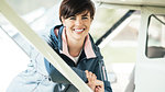 Young pilot woman leaning on an airplane and smiling at camera, travel and aviation concept