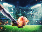 Soccer player with soccerball on fire at the illuminated stadium during the match