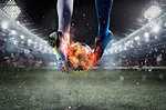 Soccer players with soccerball on fire at the illuminated stadium during the match