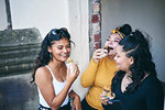 Young woman with teenage sisters eating cakes in doorway