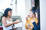 Young woman with teenage sisters while eating cakes in doorway