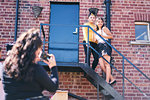 Young woman and her teenage sister being photographed  on fire escape