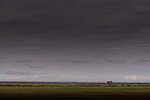 Dark coastal landscape with distant truck, Selfoss, Arnessysla, Iceland