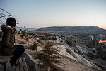 Woman enjoying view and display of hot air balloons in valley, Göreme, Cappadocia, Nevsehir, Turkey