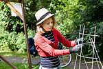 Mid adult woman tying trellis in her garden