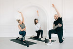 Fitness instructor teaching women stretching arm in studio