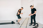 Fitness instructor observing man using agility ladder in studio