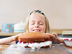 Girl baking a cake, pressing top cake sponge at kitchen table