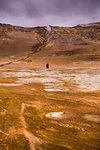 Distant view of two male tourists walking through geothermal landscape, Namaskard hverir, Myvatn, Iceland